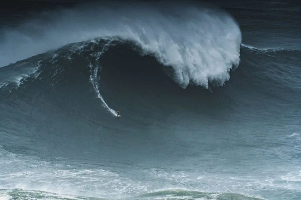 a surfer surfing a giant wave at nazare portugal