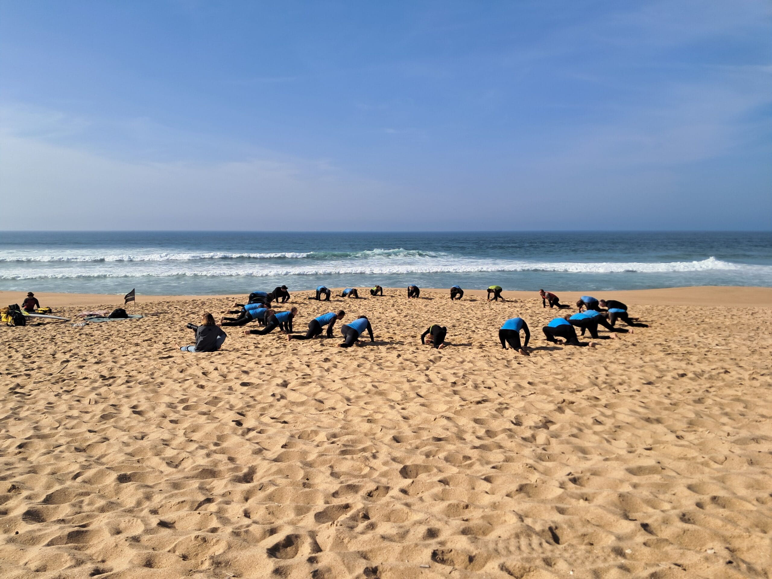 Beginner surf lesson in Portugal doing warm-up on the sand before entering the water