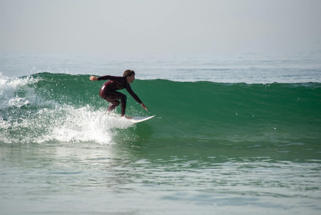 Surfer riding a clean green wave in Portugal during autumn, Peniche coast